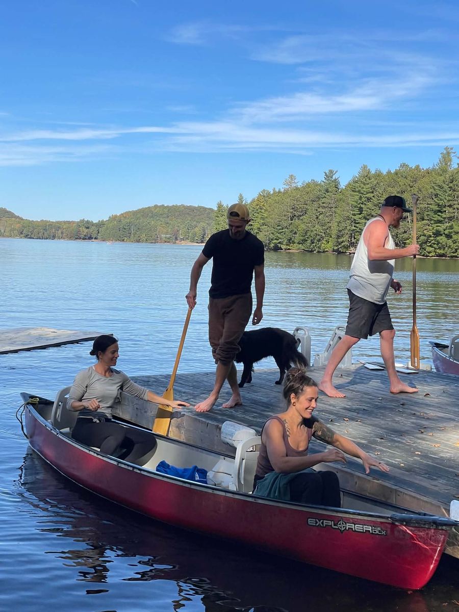 Practitioners launching a canoe from the dock on a sunny day